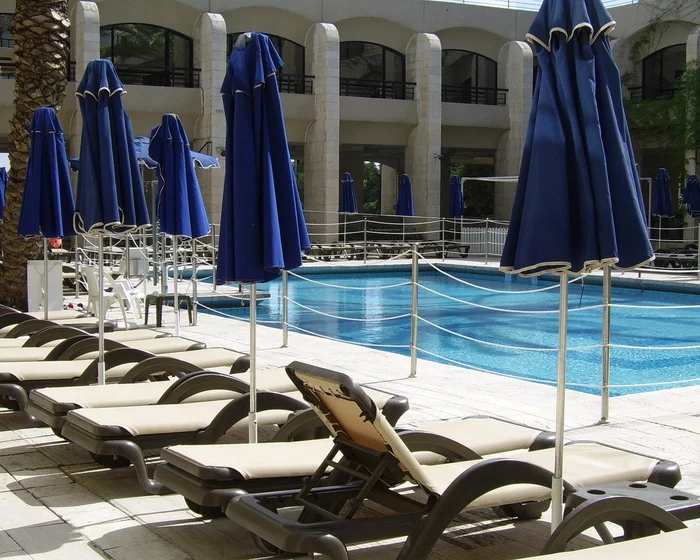 A commercial pool at an apartment community with lounge chairs, umbrellas and a fenced deck